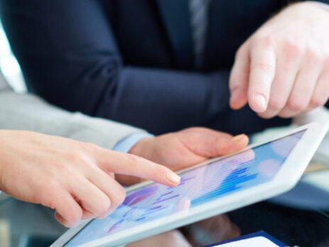 Image of human hands during discussion of business document in touchscreen at meeting